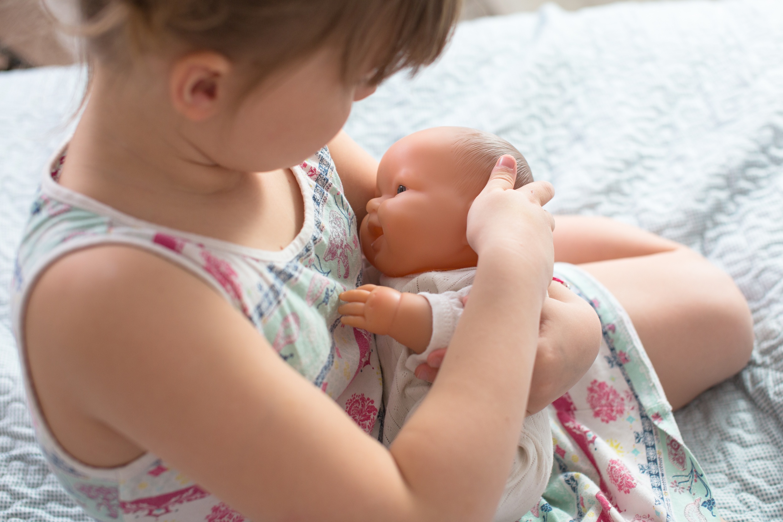 kid-girl-playing-with-doll-breastfeeding-care.jpg